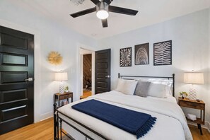 A bedroom with a bed, two bedside tables, a ceiling fan, and three wall-mounted artworks. - The Glow-up House Pool Spa Glam Room (Phoenix)