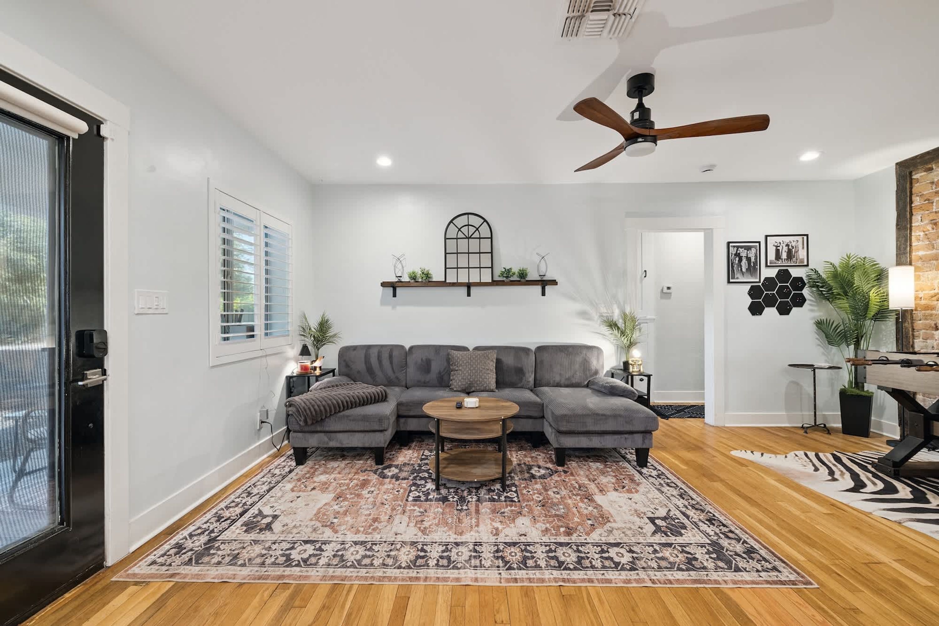 A modern living room with a sectional sofa, a coffee table, and a ceiling fan.