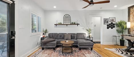 A modern living room with a sectional sofa, a coffee table, and a ceiling fan.