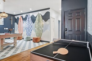 A room with a ping pong table, a pool table, and a wall with surfboard designs. - Golf Sim Theater Games Walk to Beach Sleeps 28 (North Myrtle Beach)