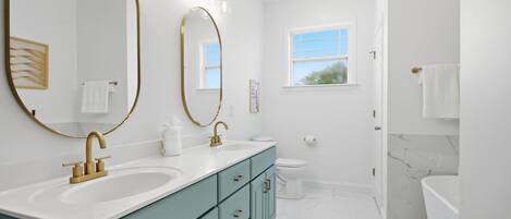 A modern bathroom with two sinks, a toilet, and a shower area.