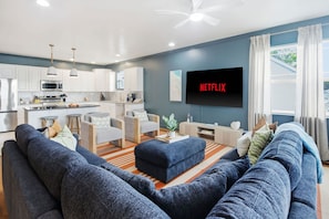 Un salon moderne avec un grand canapé, une table basse et un téléviseur fixé au mur.