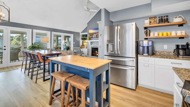 Una cocina moderna con una isla central, electrodomésticos de acero inoxidable y una zona de comedor con taburetes de bar.
