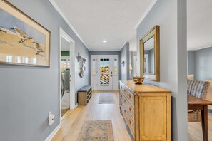 A hallway with a wooden dresser, a mirror, and a framed artwork on the wall. - Sleeps 24 Waterfront Dock Golf Cart Walk to Beach (Pawleys Island)