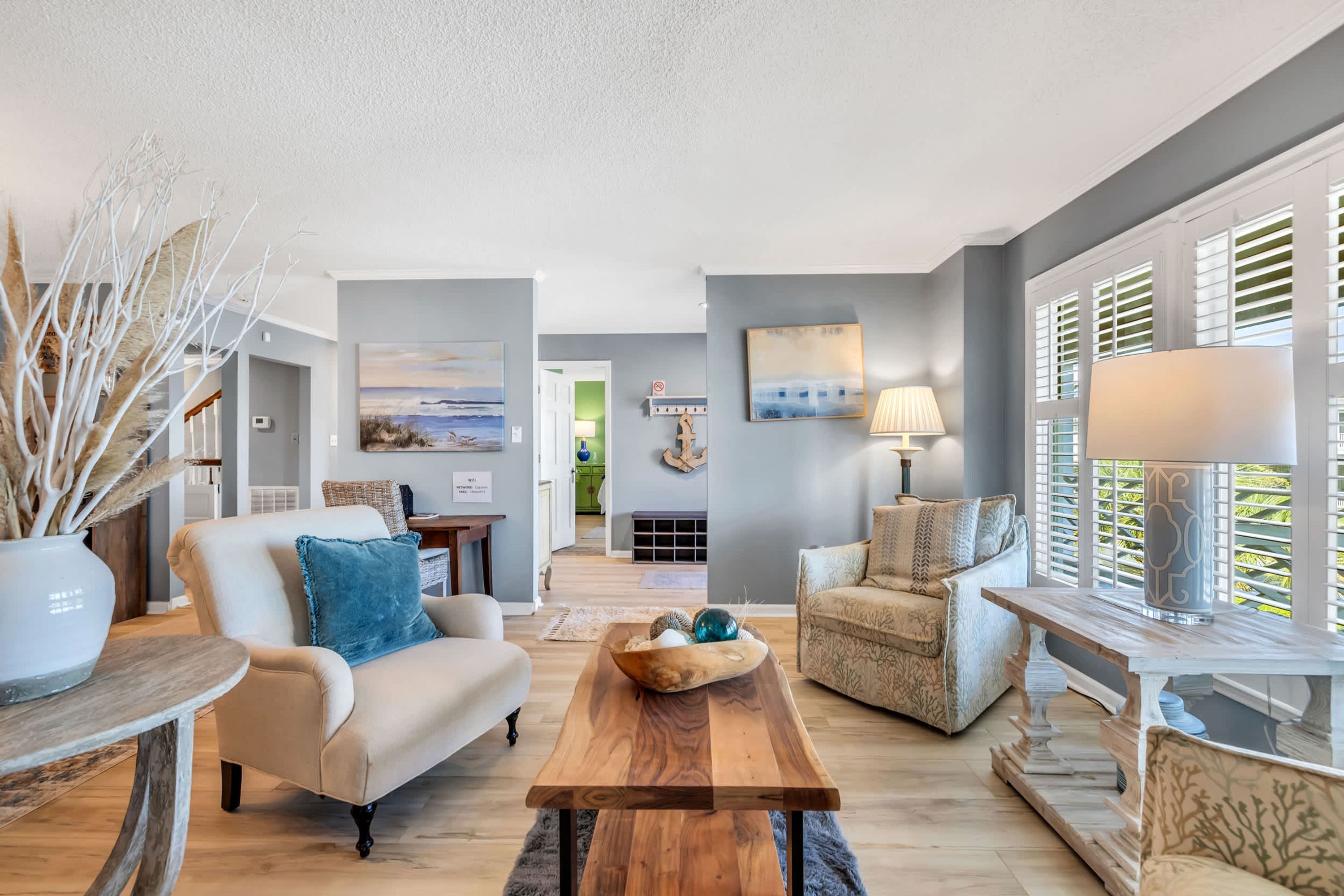 A modern living room with a beige sofa, a wooden coffee table, and a patterned armchair.