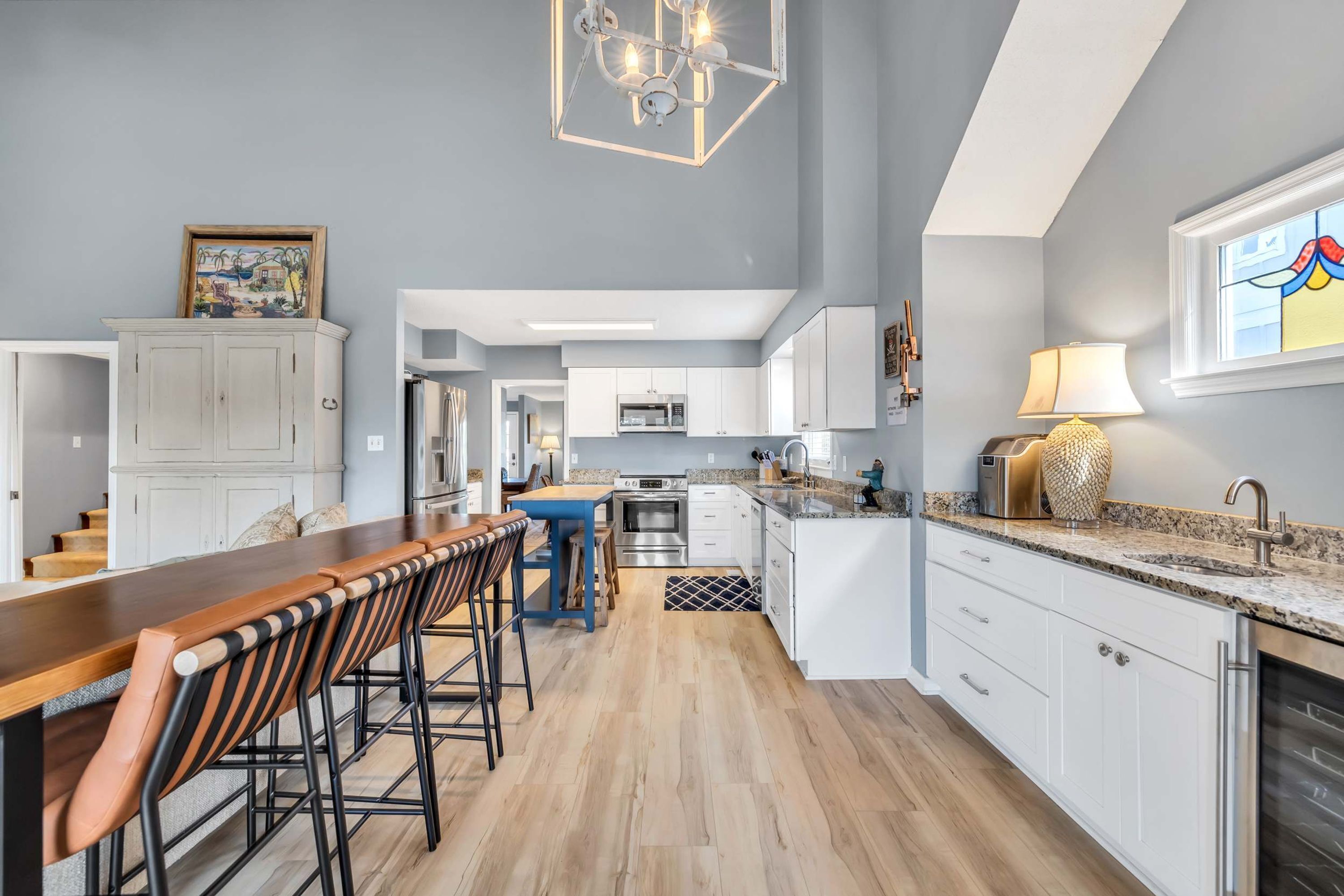 Een moderne keuken met witte kasten, een houten bar en een kroonluchter.