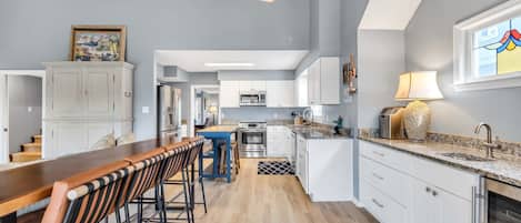 Een moderne keuken met witte kasten, een houten bar en een kroonluchter.