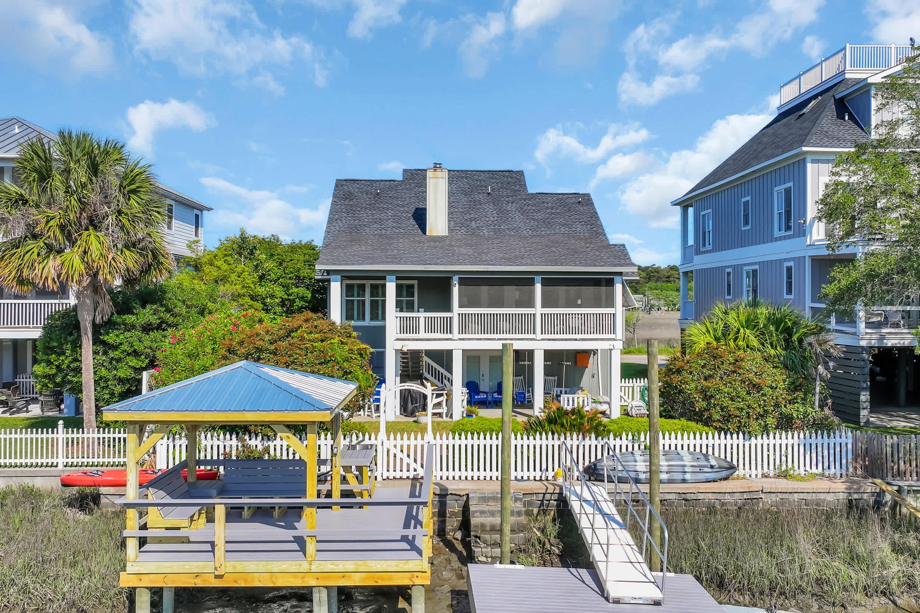 A waterfront property with a dock, a covered seating area, and a two-story building with a balcony.
