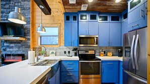 A modern kitchen with blue cabinets, a stainless steel refrigerator, and a built-in oven. - Retro Retreat Stargazing Dome Sauna Hot Tub (Broken Bow)