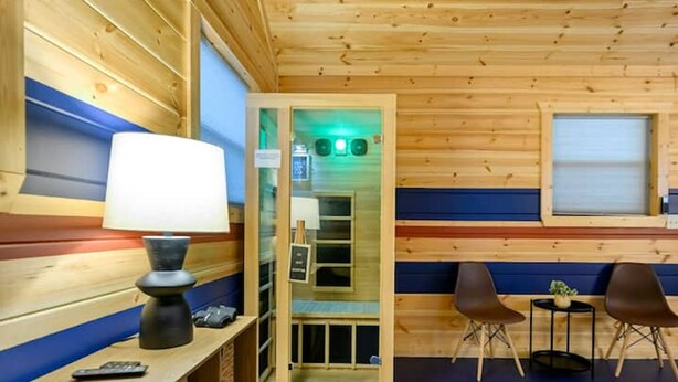 A wooden cabin interior with a desk, lamp, chairs, and a small table with a plant. - Retro Retreat Stargazing Dome Sauna Hot Tub (Broken Bow)