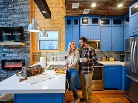 Una cocina moderna con armarios azules, una pared de piedra y una chimenea.