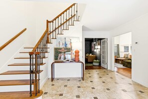 A staircase with wooden steps and black balusters leading to a landing with a white console table. - Gathering House Movie Game Room Hot Tub Pool (San Antonio)
