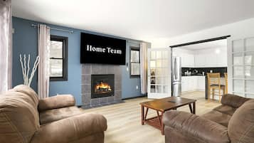 A modern living room with a fireplace, a flat-screen TV, and a dining area.