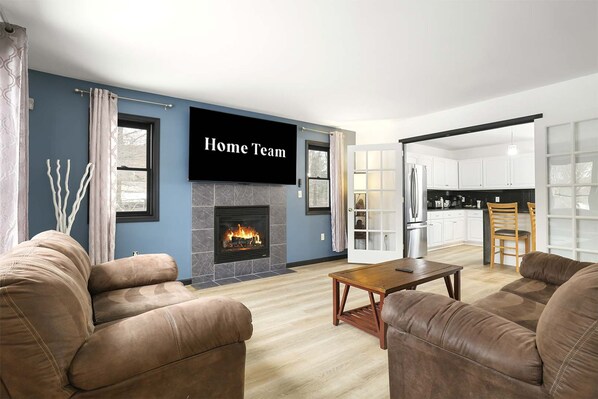 A modern living room with a fireplace, a flat-screen TV, and a dining area. - Sleeps 14 Hot Tub Sauna Game Room Fire Pit (Long Pond)