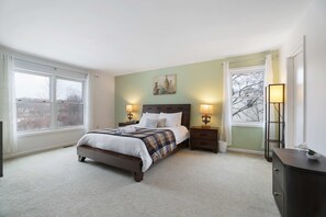 A bedroom with a bed, two bedside tables, a nightstand, a window, and a door. - Sleeps 14 Hot Tub Sauna Game Room Fire Pit (Long Pond)