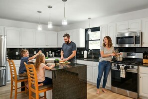 A modern kitchen with white cabinets, a central island, stainless steel appliances, and pendant lighting. - Sleeps 14 Hot Tub Sauna Game Room Fire Pit (Long Pond)