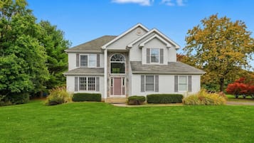 A two-story house with a front porch, a garage, and a well-maintained lawn.
