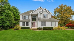 A two-story house with a front porch, a garage, and a well-maintained lawn. - Sleeps 14 Hot Tub Sauna Game Room Fire Pit (Long Pond)