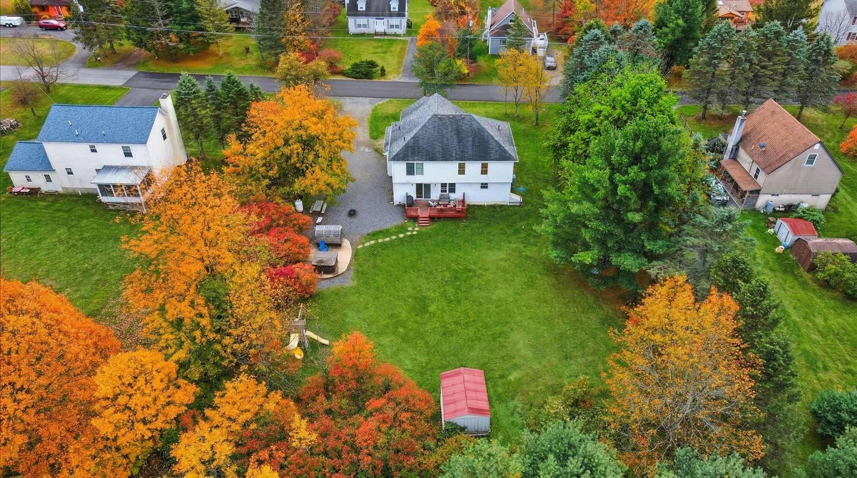 Un quartier résidentiel avec des maisons, une pelouse bien entretenue et des arbres aux couleurs automnales.