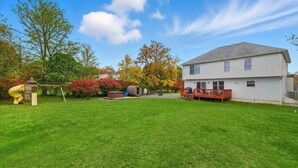 Ein Wohnhaus mit gepflegtem Rasen, einer Spielanlage, einem Whirlpool und einer Terrasse.