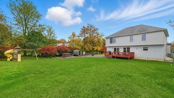 A residential property with a well-maintained lawn, a play structure, a hot tub, and a deck.