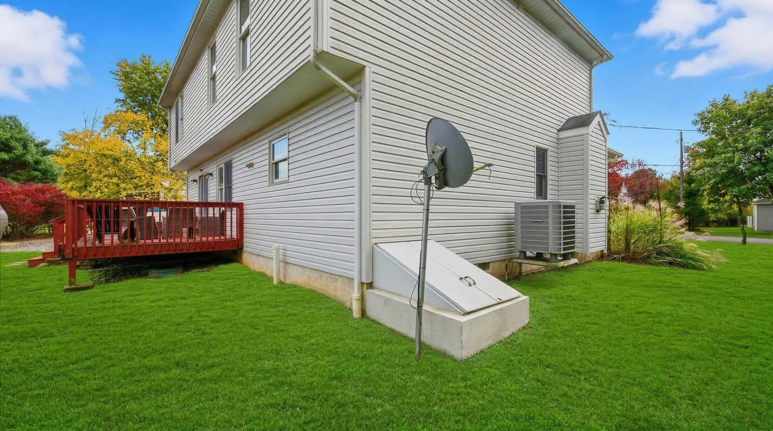 Ein zweistöckiges Haus mit roter Terrasse, Satellitenschüssel und Klimaanlage.