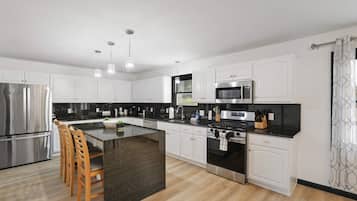 A modern kitchen with white cabinetry, stainless steel appliances, a central island, and pendant lighting.