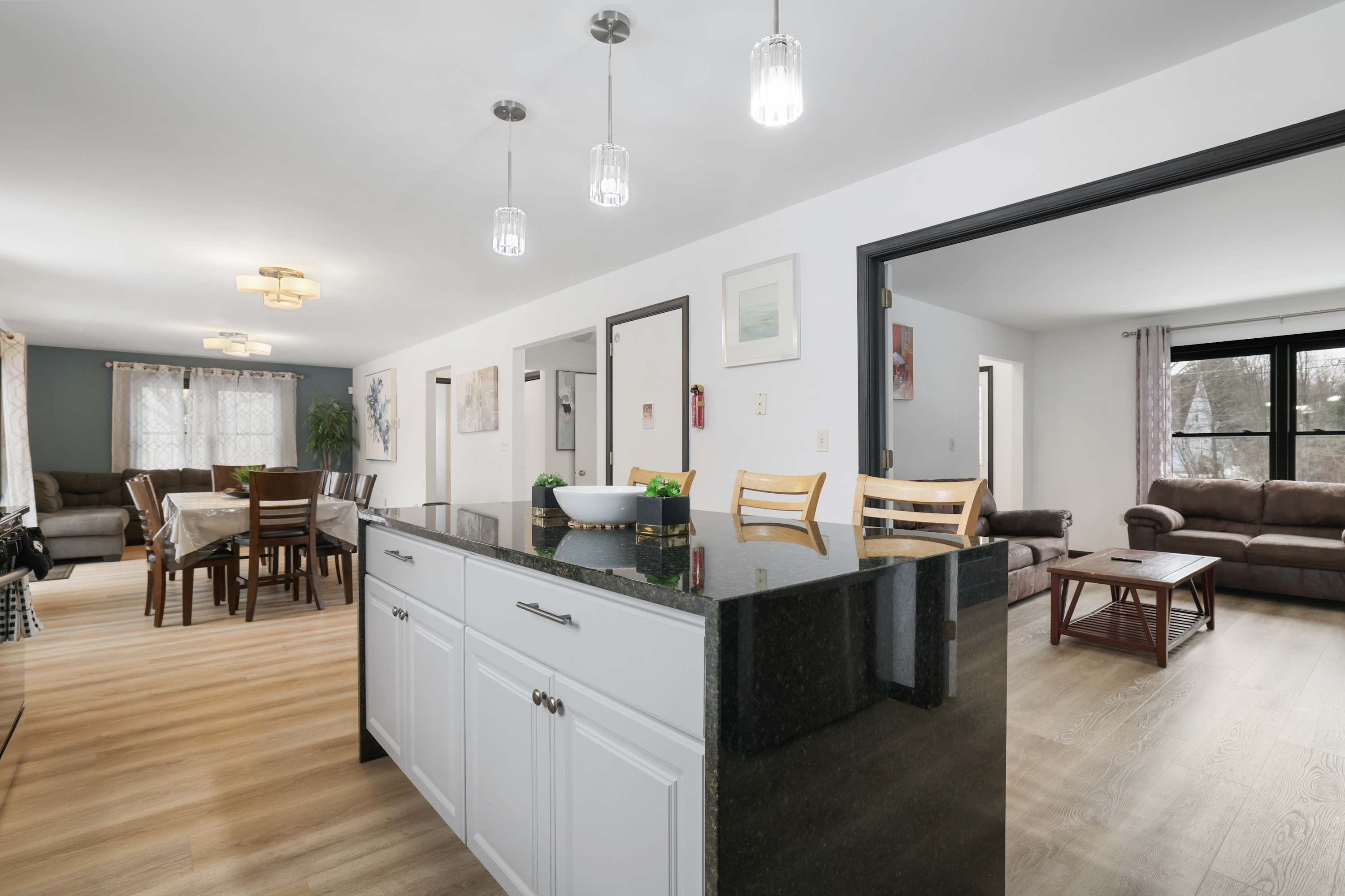 A modern kitchen with a central island, dining area with chairs, and a living room with a sofa and a coffee table.