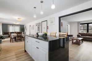 A modern kitchen with a central island, dining area with chairs, and a living room with a sofa and a coffee table. - Sleeps 14 Hot Tub Sauna Game Room Fire Pit (Long Pond)