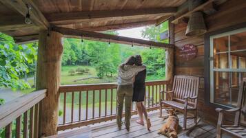 A wooden porch with a bench and a dog.