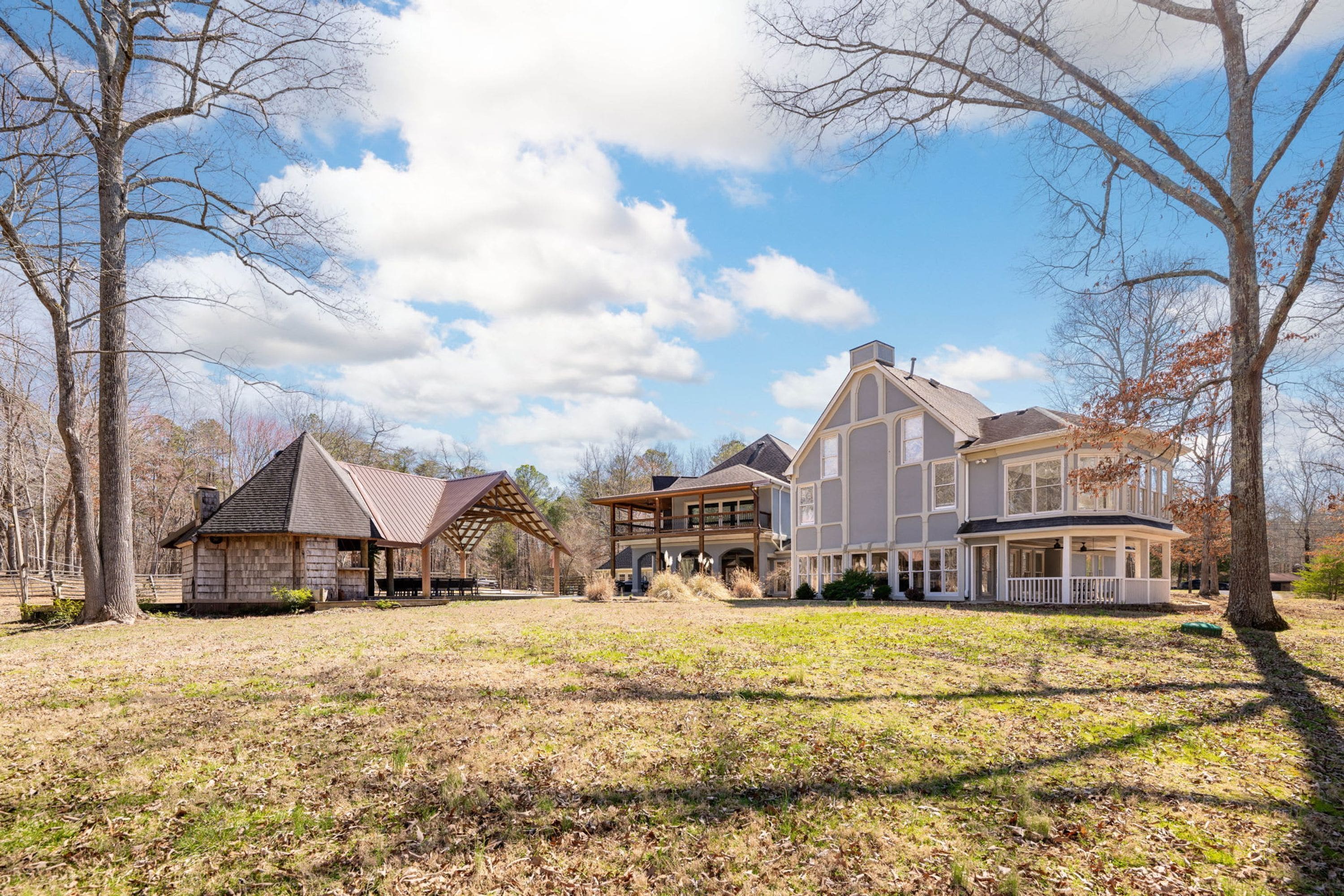 A large, multi-story house with a covered patio and a separate cabin-like structure.