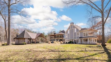 A large, multi-story house with a covered patio and a separate cabin-like structure.