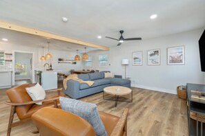 A modern living room with a sofa, chairs, a coffee table, and a dining area with a table and chairs. - Sleeps 14 Outdoor Patio Firepit Game Room (Fort Walton Beach)