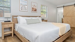 Une chambre à coucher avec un grand lit, une tête de lit en bois, deux tables de chevet, une commode et une armoire en bois.