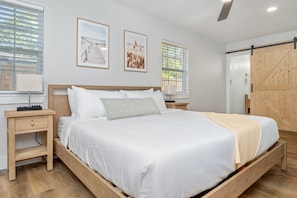 Ein Schlafzimmer mit einem großen Bett, einem Holzkopfteil, zwei Nachttischen, einem Beistelltisch und einem Holzschrank.