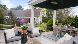 A covered outdoor seating area with a sofa, chairs, and a table. - Luxury Lakeview Estate w Indoor Pool Golf Sim (Ithaca)