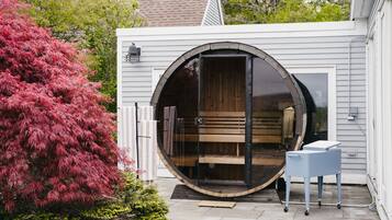 A circular room with a bench and a small table, a sliding door, and a white exterior wall.