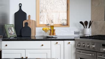 A kitchen with white cabinets, a black countertop, a stove, and a window with a view of trees.