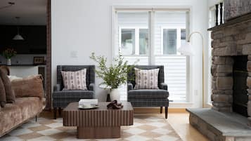 A living room with two armchairs, a coffee table, a fireplace, and a large window.