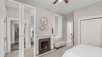A bedroom with a fireplace, a bed, and a ceiling fan.