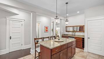 A modern kitchen with granite countertops, wooden cabinets, and pendant lighting.