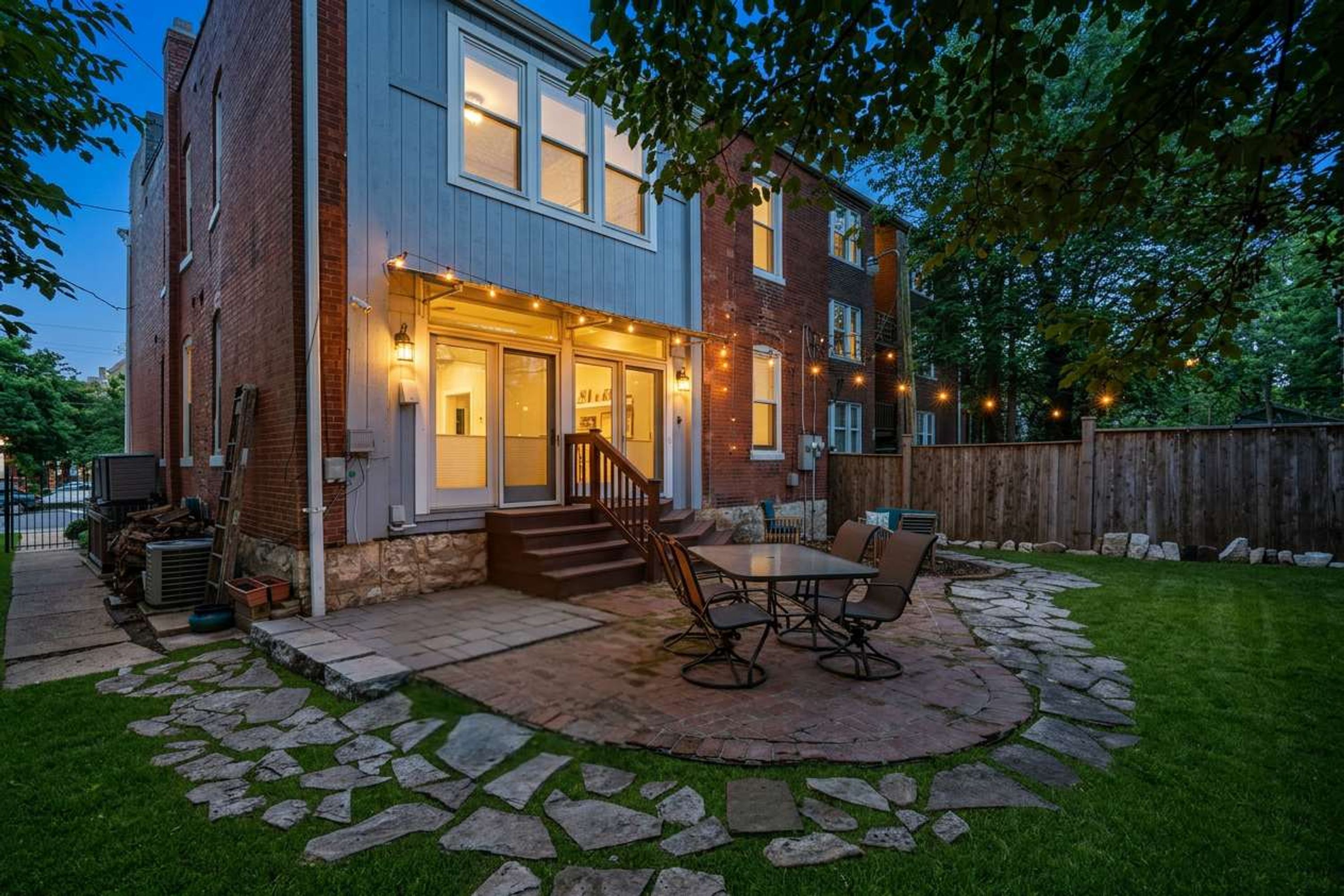 A two-story brick house with a stone patio and outdoor seating area.