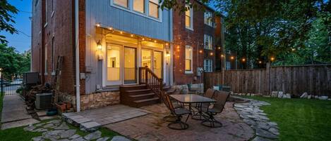 A two-story brick house with a stone patio and outdoor seating area.
