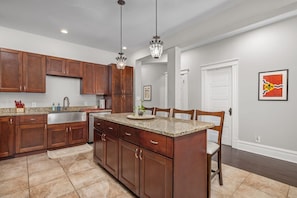 A kitchen with wooden cabinets, granite countertops, a central island, and pendant lighting. - Walk to Forest Park Fire Pit Porch Swing (St. Louis)