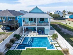 Ein zweistöckiges Haus mit Swimmingpool, Balkon und überdachter Terrasse.