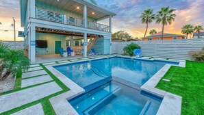 A two-story house with a swimming pool, outdoor seating, and palm trees. - Glory Daze Private Pool Ice Maker EV Charger (Port Aransas)