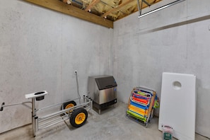 A utility room with a metal cart, a large appliance, and a white cabinet. - Glory Daze Private Pool Ice Maker EV Charger (Port Aransas)