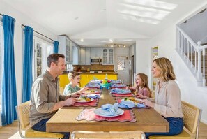 A family dining in a modern kitchen with white cabinets, a wooden dining table, and a staircase. - Sleeps 20 Sport Court Game Room Sauna Spa (Asheville)