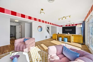 Moderni olohuone, jossa on sohva, sohvapöytä ja televisio. Huoneesta johtaa portaikko yläkertaan.