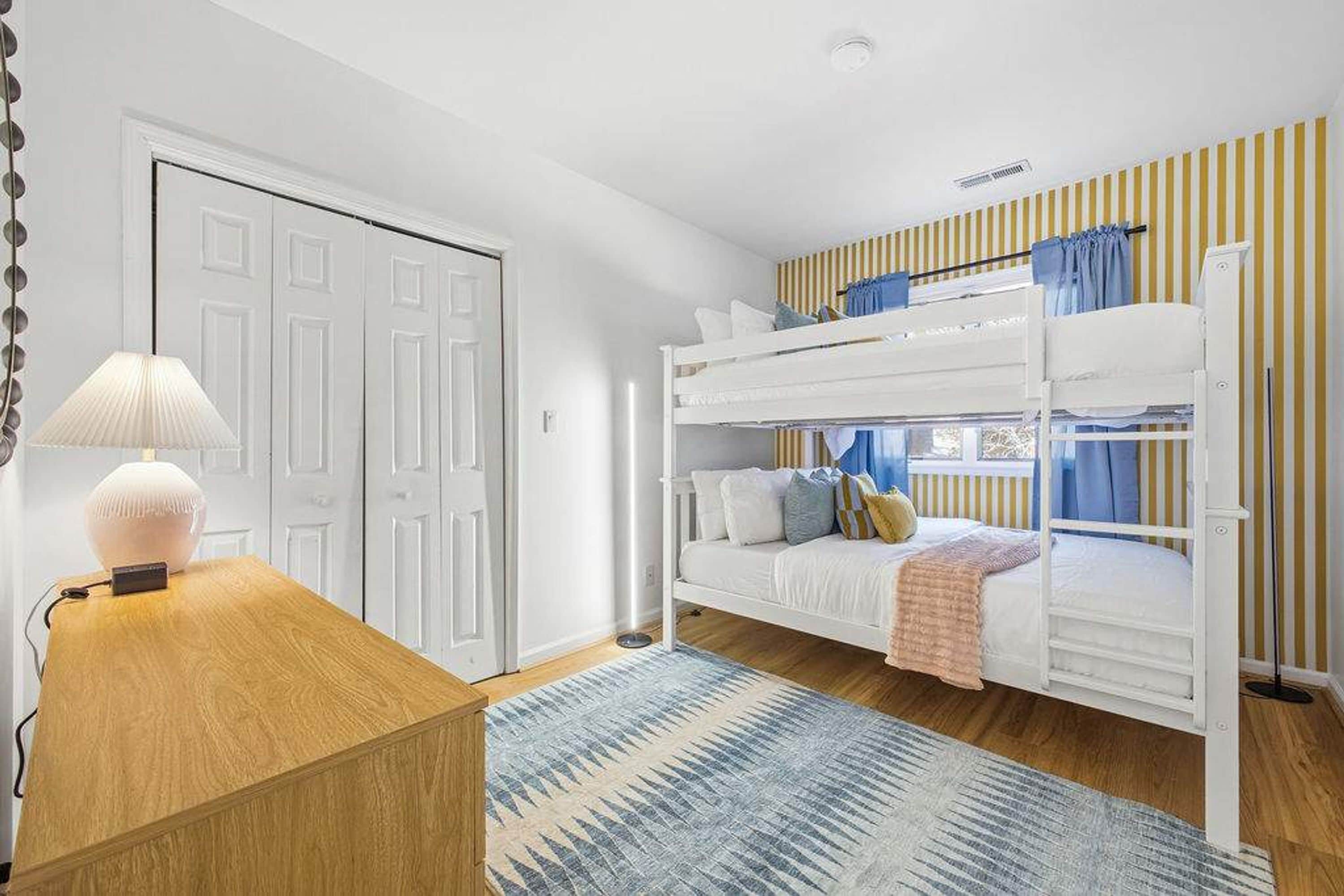 Une chambre avec un lit superposé, un bureau avec une lampe et une porte.